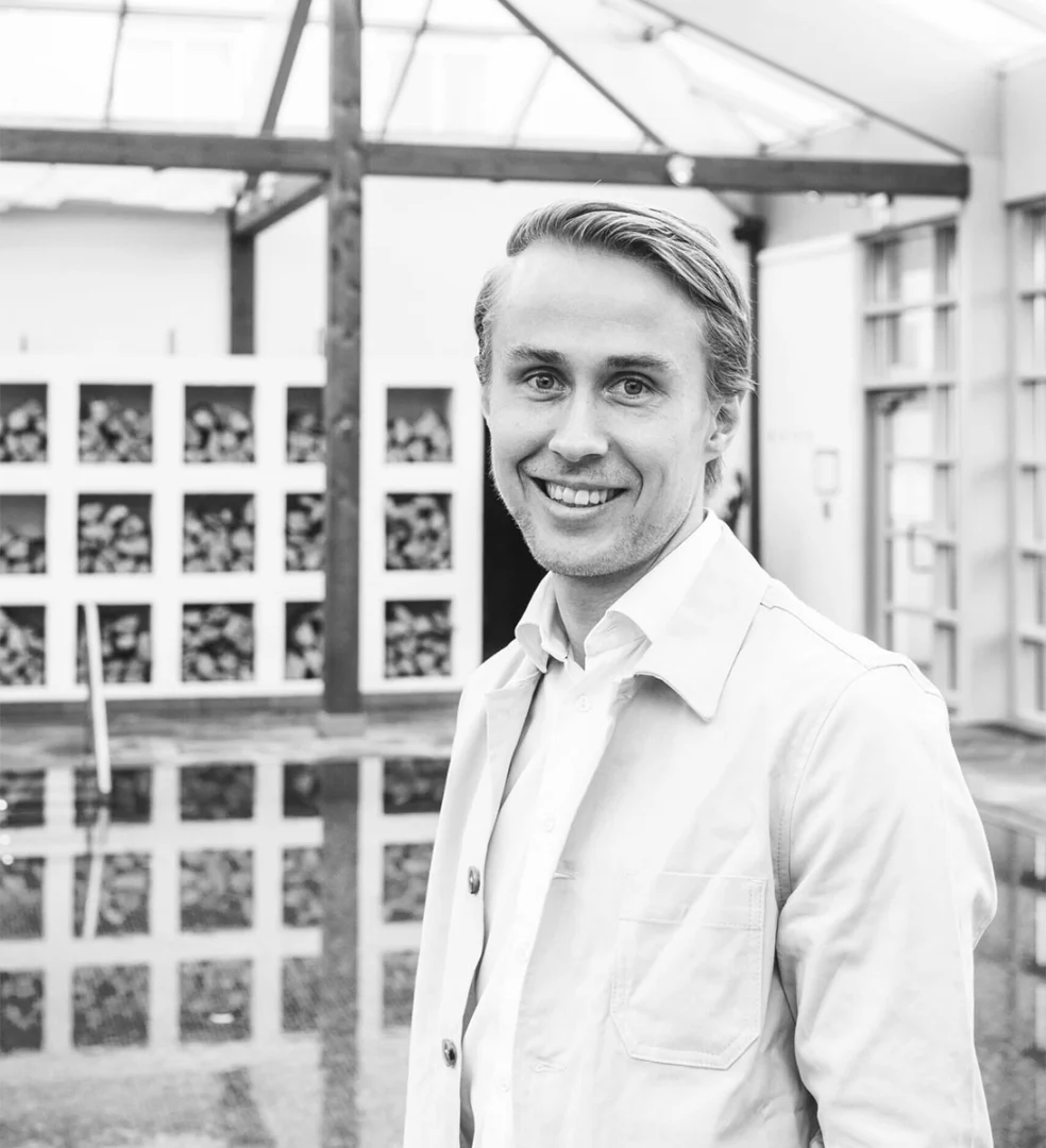 Leende man i vit skjorta på Falkenberg Strandbads ljusa konferensanläggning med modern arkitektur