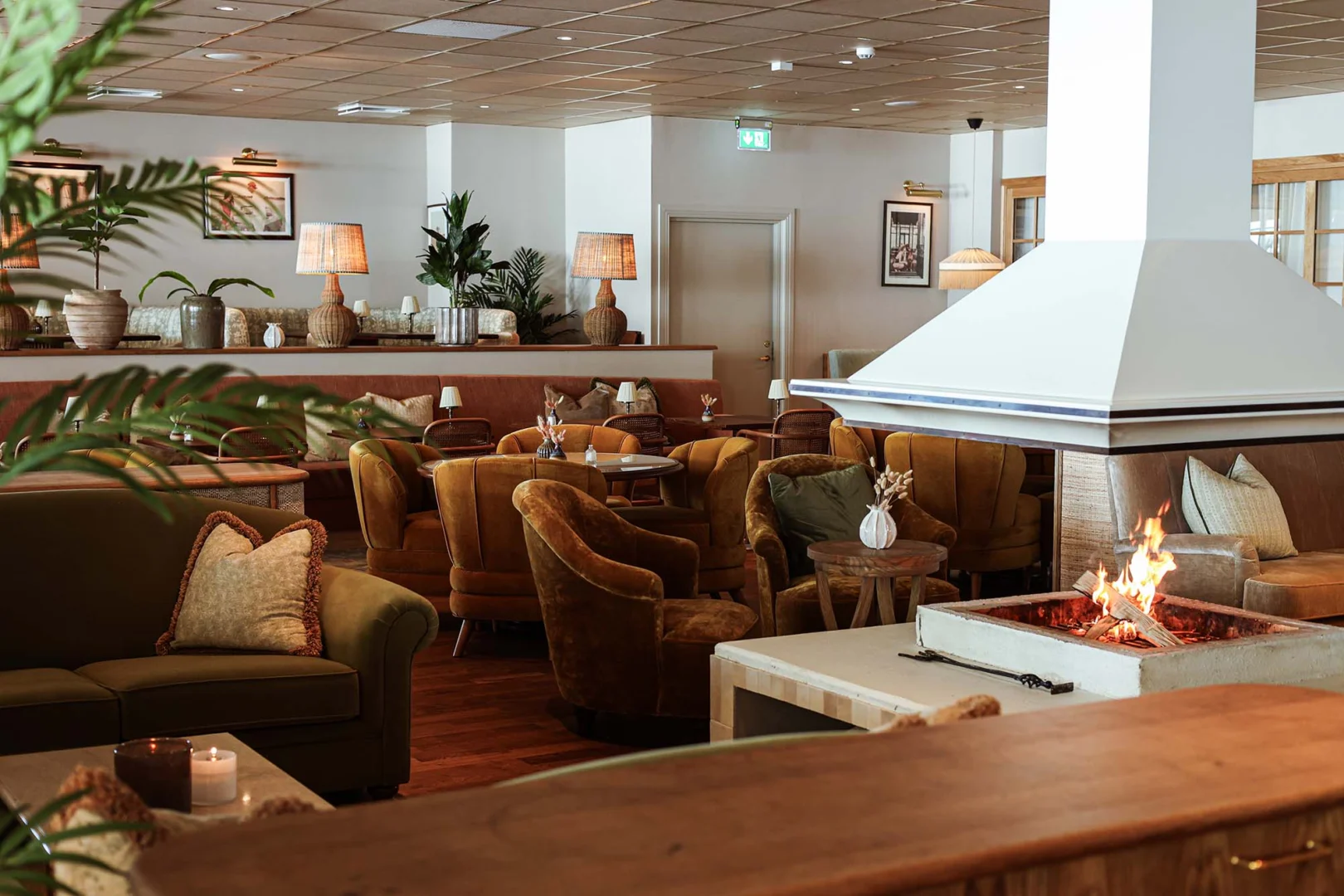 Mysig lounge med öppen spis och lyxiga fåtöljer i varma toner på Falkenberg Strandbad