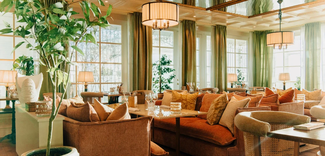 Elegant konferenslounge med varma orangea soffor och havsutsikt genom stora fönster på Falkenberg Strandbad