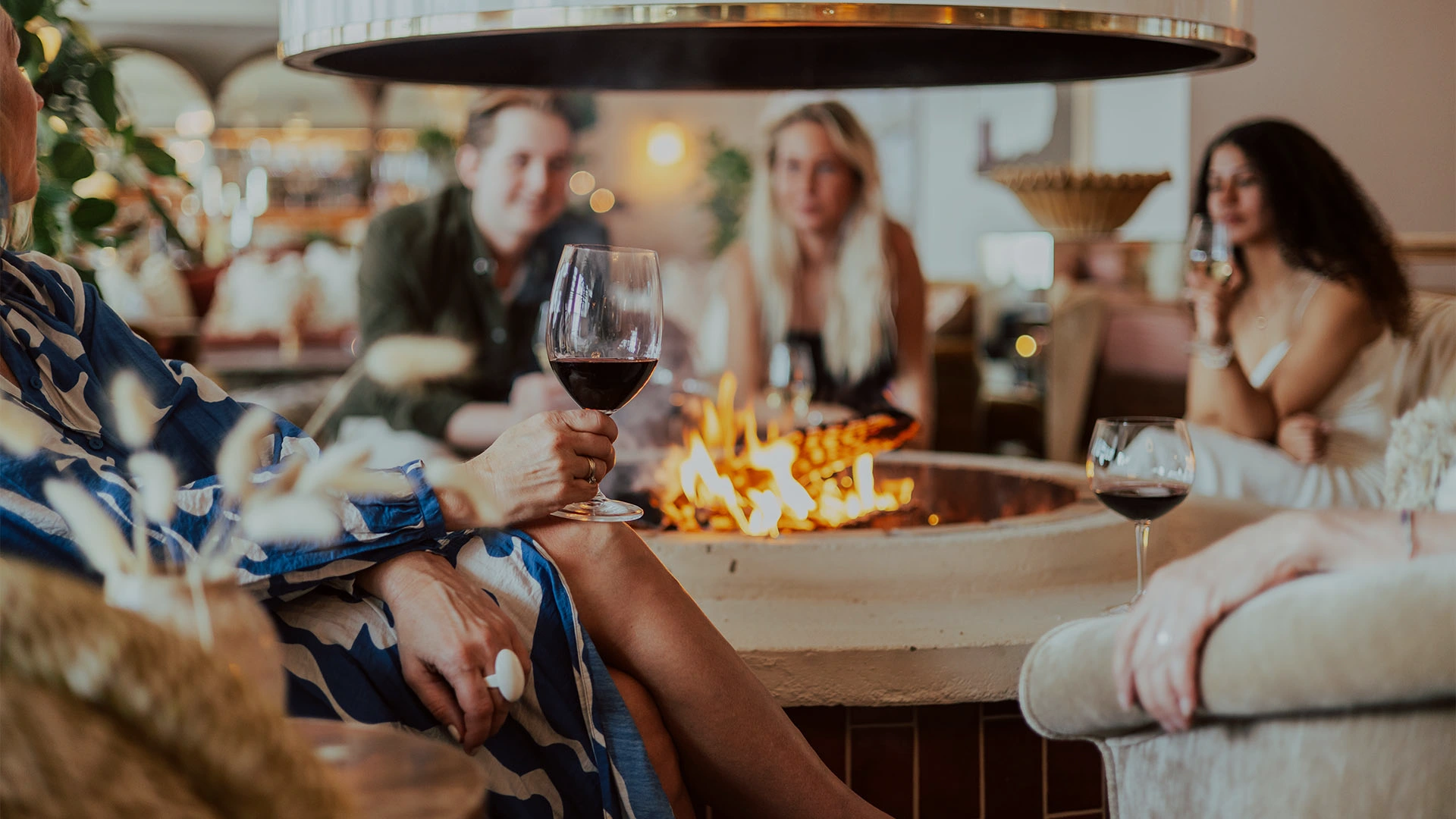 Gäster som njuter av vin framför öppen eld i Brasserie Famille på Falkenberg Strandbad