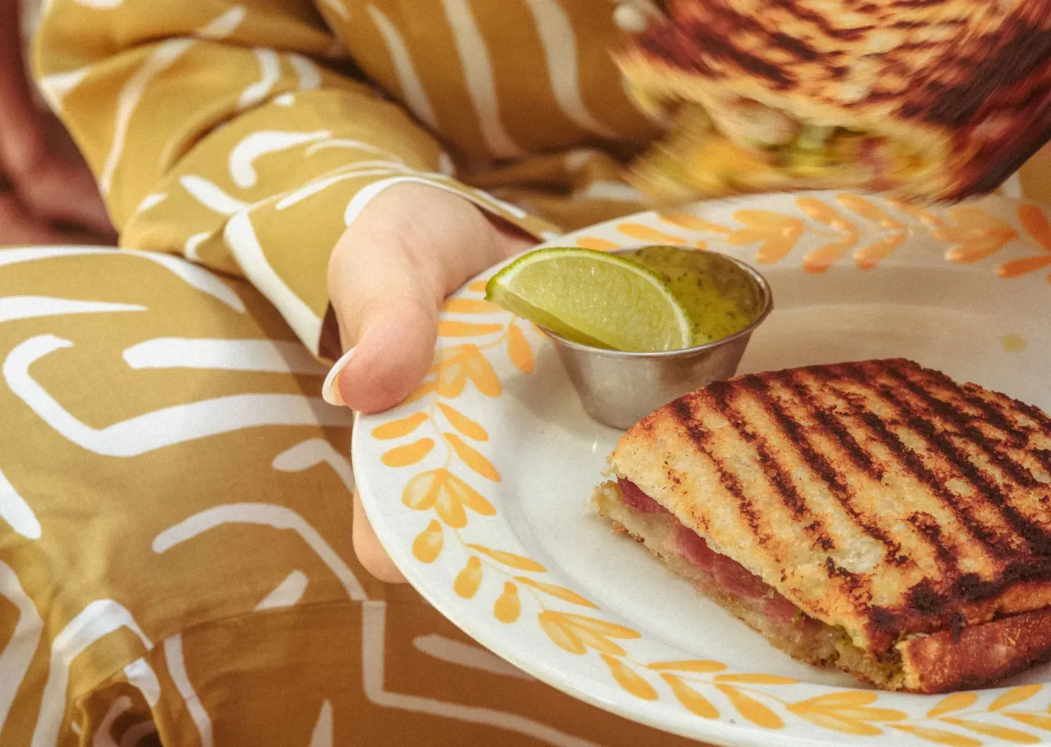 Grillad sandwich med skinka serverad med limeklyfta på vit tallrik