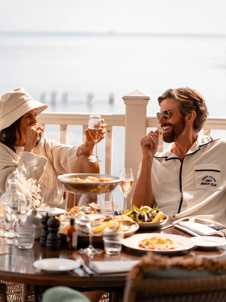 Par som äter lunch och dricker vin med havsutsikt under sommar i Falkenberg på Falkenberg Strandbad